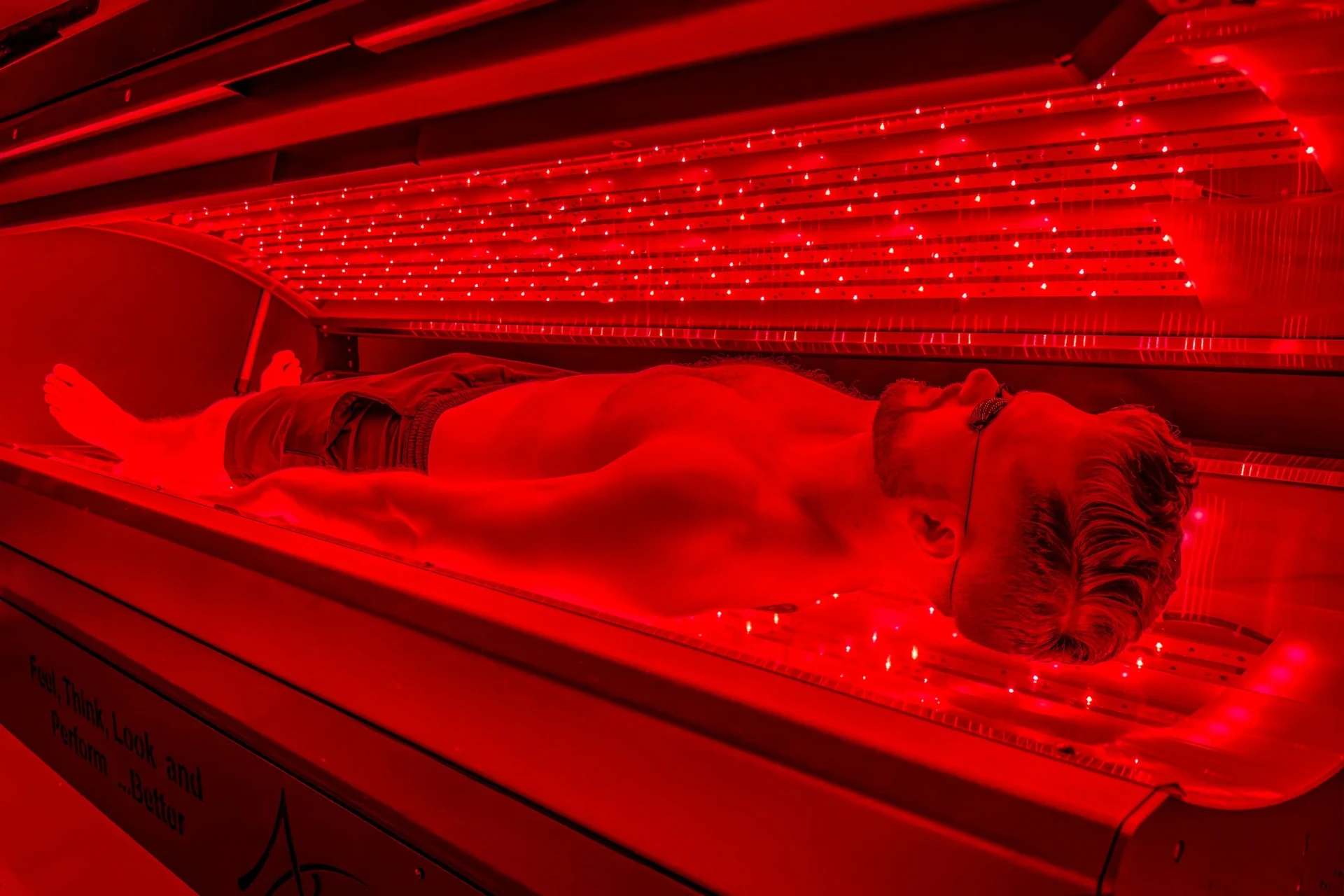 Red light therapy bed — full-body photobiomodulation for recovery and wellness Man using full-body red light therapy Pro-Bed for muscle recovery at REDSOL Wellness Club League City TX